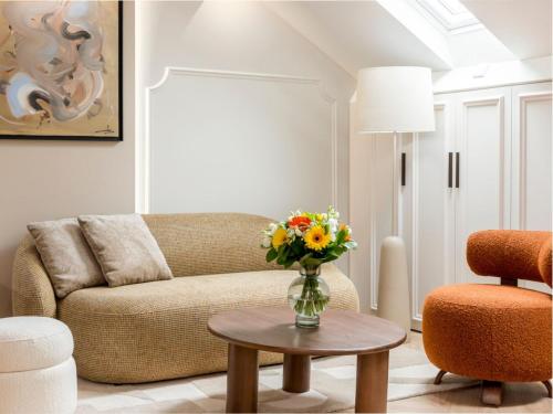 - un salon avec un canapé et un vase de fleurs sur une table dans l'établissement Merveil - Luxury Suite - Champs Elysees - St Cyr I, à Paris