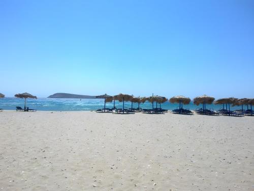 a beach with chairs and umbrellas and the ocean at Blue Xenia Villas Paros in Chrissi Akti