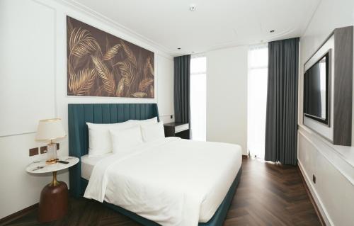 a bedroom with a white bed and a television at Belliss Hotel And Spa Dai Lai in Phúc Yên