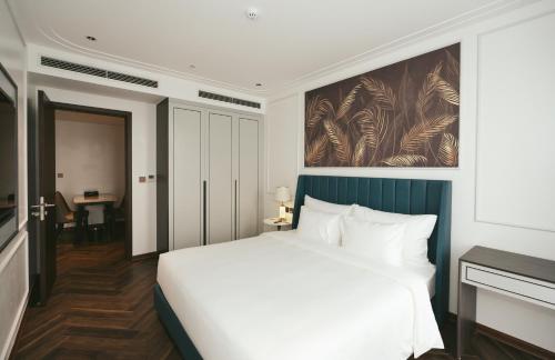 a bedroom with a white bed and a painting on the wall at Belliss Hotel And Spa Dai Lai in Phúc Yên