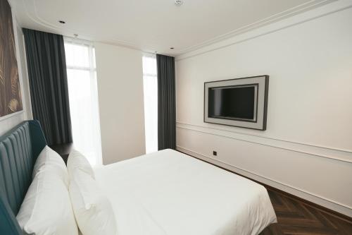 a bedroom with a bed and a tv on the wall at Belliss Hotel And Spa Dai Lai in Phúc Yên