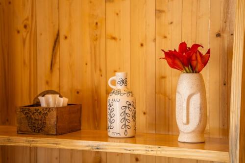 a shelf with a white vase and a red flower at Ila by Aaryam, Kanatal in Chamba
