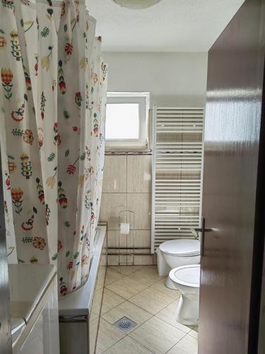 a bathroom with a toilet and a shower curtain at Apartman Barbara in Grabovac