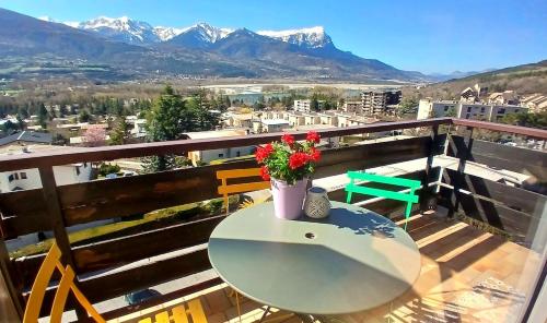 a table and chairs on a balcony with mountains at Le petit perchoir du lac in Embrun