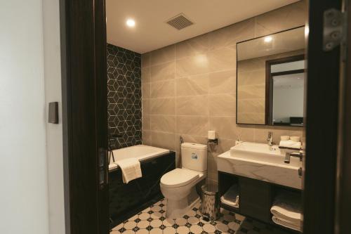 a bathroom with a toilet and a sink and a mirror at Belliss Hotel And Spa Dai Lai in Phúc Yên