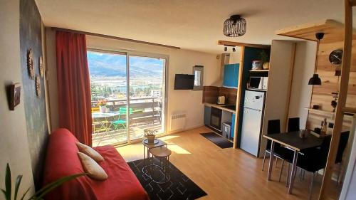 a living room with a red couch and a large window at Le petit perchoir du lac in Embrun