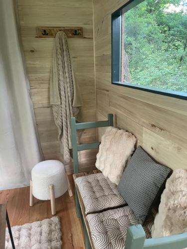 une petite pièce avec un canapé, une chaise et une fenêtre dans l'établissement Ti'Nid, cabane chaleureuse plongée dans la nature, à Montignac