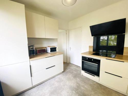 une cuisine avec des armoires blanches et un four noir dans l'établissement Maison avec WIFI, jardin à 320m de la plage à TREGASTEL - Réf 183, à Trégastel