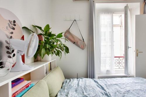 - une chambre avec un lit, une plante et une fenêtre dans l'établissement Charmant appart cosy et central, à Paris