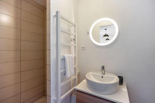 une salle de bain blanche avec un lavabo et un miroir dans l'établissement Le Cosy de la Craffe - Proche Porte Désilles, à Nancy