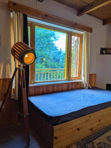 a bedroom with a bed with a large window at The heavens place wooden room in Nagar