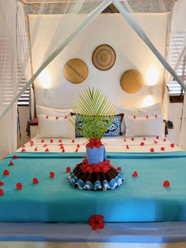 a room with a bed with a table with red flowers at SeVi Boutique Hotel in Matemwe