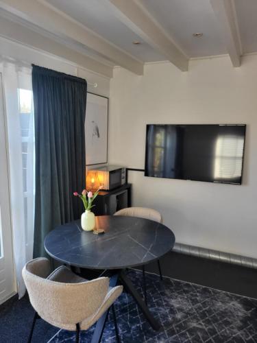 a room with a table and chairs and a television at Je B&B Giethoorn, incl fietsen! in Giethoorn