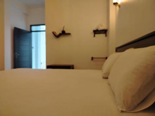 a bedroom with a bed with two shelves on the wall at Diora Hotel in Ratnapura