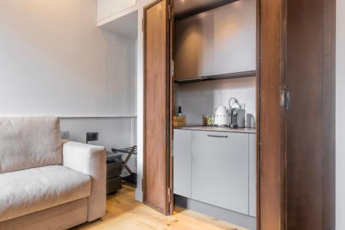 a living room with a chair and a kitchen at Spiriti Home Apartment , New Opening Piazza di Pietra in Rome