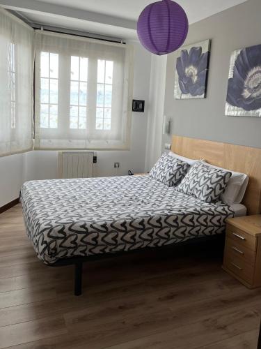 a bedroom with a bed with a black and white comforter at Apartamentos Tajamar in Lastres
