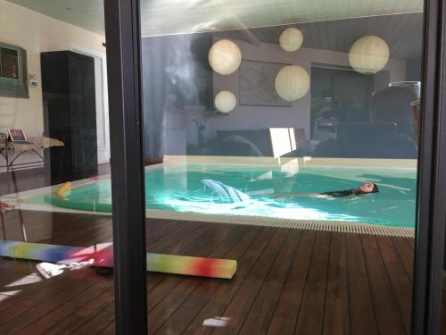 une personne allongée dans une piscine dans l'établissement chambre d hôtes les trois châteaux piscine intérieure chauffée, à Notre-Dame-de-Riez