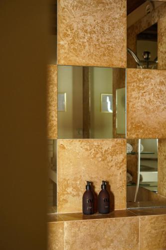 uno specchio da bagno con due dispenser di sapone su uno scaffale di L'Absinthe Hôtel a Honfleur