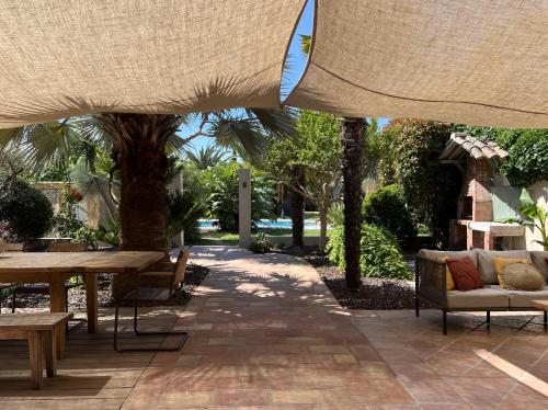 un patio avec une table et des chaises sous un parasol dans l'établissement Maison jardin tropicale piscine - Quatre Murs Et Un Toit, à Hyères