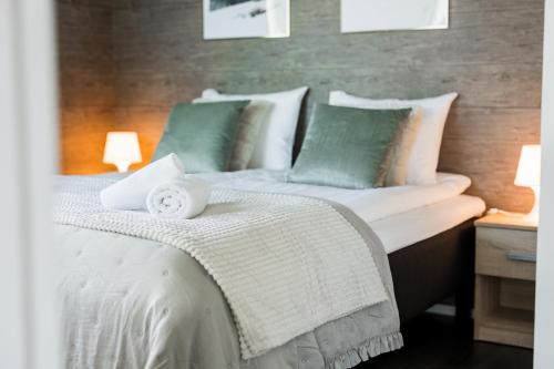 a bedroom with a bed with white and green pillows at Calm Suite with Sauna and Free Garage - Heart of Lapland in Rovaniemi