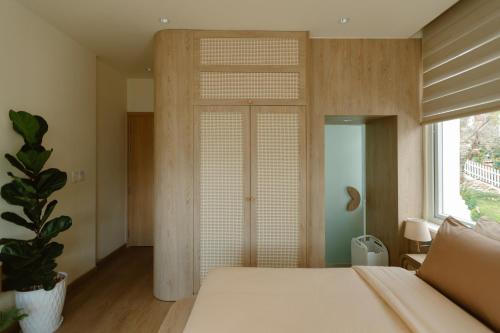 a bedroom with a white bed and a window at The Gardener by WeDalat in Da Lat