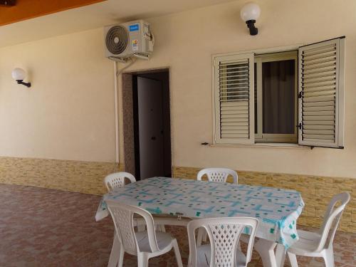 a dining room with a table and white chairs at B&B Villa Matari in Fontane Bianche
