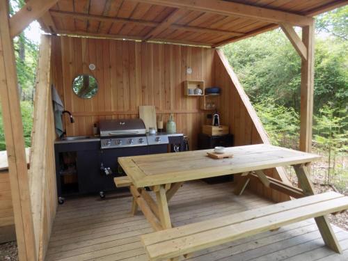 an outdoor kitchen with a wooden table and a stove at Tente familiale au bord de l'eau in Le Vigeant