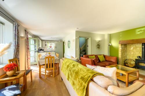 a living room with a couch and a table at Cosy Cotswold Lodge by Your Home Here - SUMMER SALE for 3 PLUS NIGHTS - ideal for families with log-burner, spa, private parking, EV recharging and heated swimming pools in Ashton Keynes