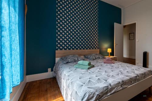 une chambre avec un lit avec un mur bleu dans l'établissement Maison en bord de Creuse - 2min d'Argenton, à Le Pêchereau