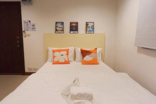 a bedroom with a white bed with orange pillows at Sampheng House in Bangkok