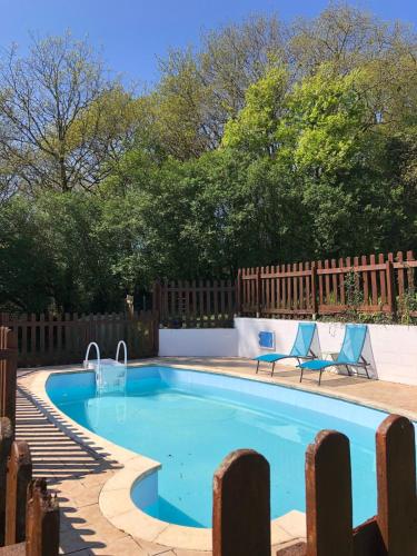 une piscine avec deux chaises et une clôture dans l'établissement Gites de la Foret du Huelgoat, à Huelgoat