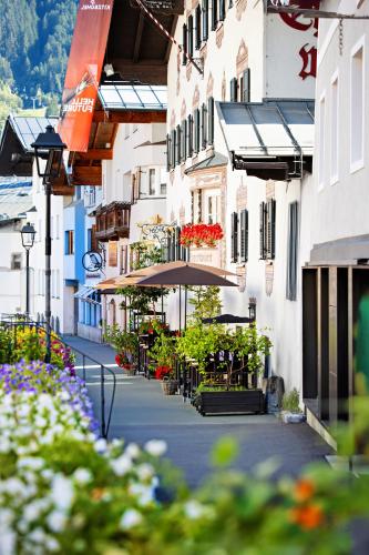 a city street with tables and chairs and flowers at Eggerwirt Kitzbühel, Hotel & Restaurant in Kitzbühel