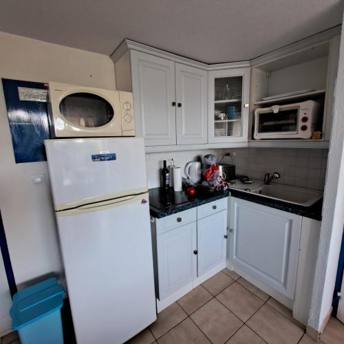 une cuisine avec des armoires blanches et un réfrigérateur blanc dans l'établissement Patios de barcares, au Barcarès