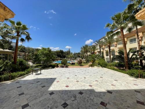 a large stone patio in front of a building with palm trees at Marina Palace in Hammamet