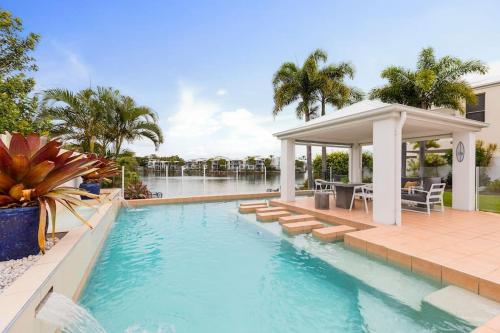 a swimming pool with a gazebo next to a house at Stunning Waterfront Coastal Retreat, sleeps 13 in Twin Waters