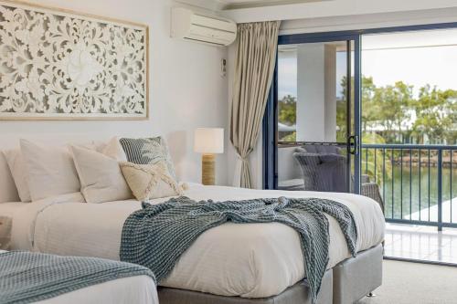 a bedroom with a bed and a balcony at Stunning Waterfront Coastal Retreat, sleeps 13 in Twin Waters