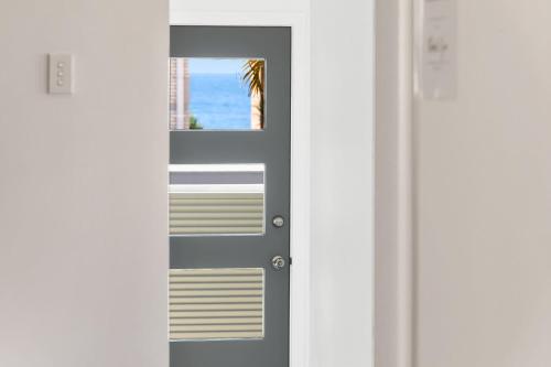a door with a view of the ocean through it at Retreat in the Heart of Alex - 3BR sleeps 11, Pool in Alexandra Headland
