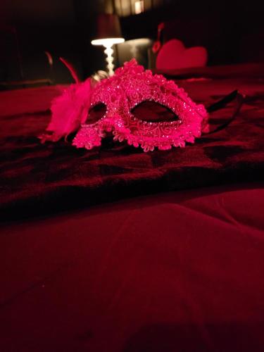 un masque rose posé sur un lit dans l'établissement Gîte romantique Le Glamour, à Mazé