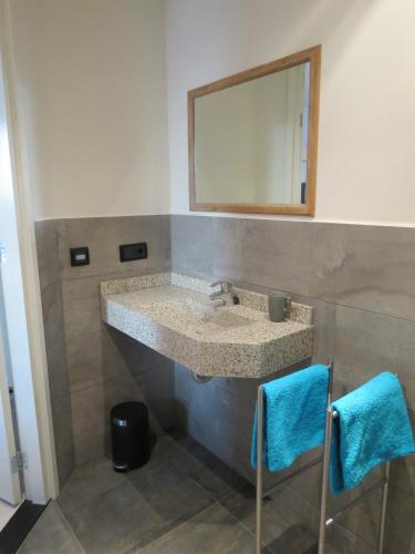 a bathroom with a sink with a mirror and two towels at Bed & Breakfast Pergama in Haaren