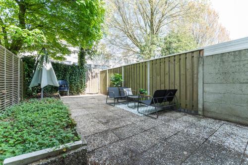 a patio with chairs and an umbrella next to a fence at Modern Stay with Wi-Fi - Tilburg in Tilburg