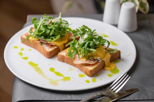 a white plate with two pieces of toast with greens on it at Black Sea Central in Odesa