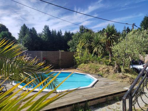une piscine dans un jardin avec une terrasse en bois dans l'établissement La néo-bretonne forestière, à Camors