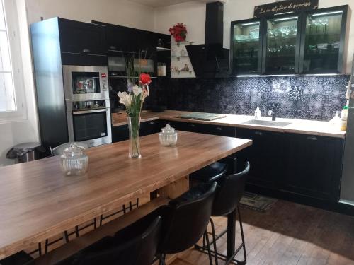 une cuisine avec une table en bois et un vase de fleurs. dans l'établissement Havre de paix, à Lalinde