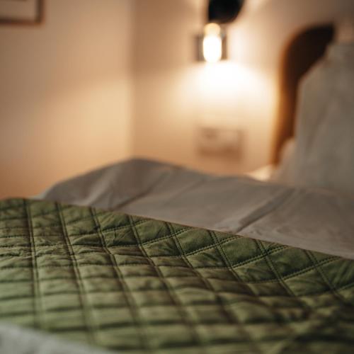 a bed with a green comforter on top of it at VillaPince in Garabonc
