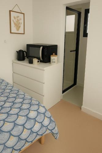 - une chambre avec un lit et un four micro-ondes sur une commode dans l'établissement Chambre privée 350 m de la mer et proche et gr34 avec coin repas et micro onde, à Plouguerneau