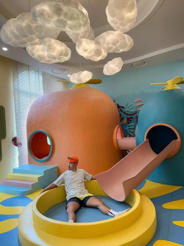 a man is sitting on a slide in a play room at Sunset town Phú Quốc in Phu Quoc