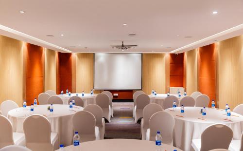 a conference room with tables and chairs and a screen at Zone Connect by The Park Coimbatore in Coimbatore