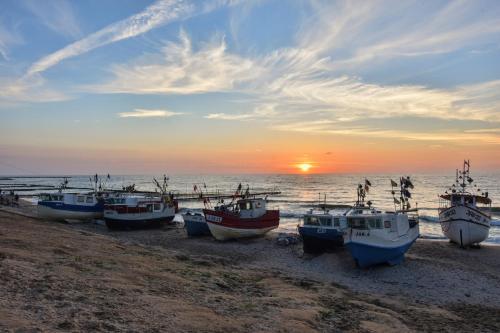 a group of boats sitting on the beach at sunset at Willa Biały Dom - Aquapark Panorama Morska All Inclusive in Jarosławiec