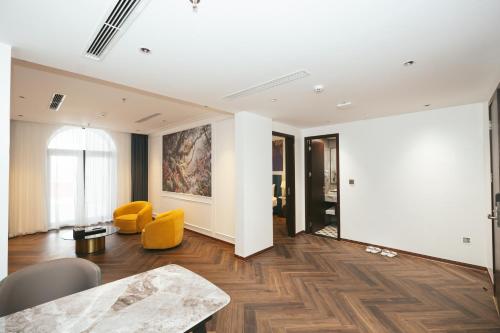 a living room with a table and yellow chairs at Belliss Hotel And Spa Dai Lai in Phúc Yên