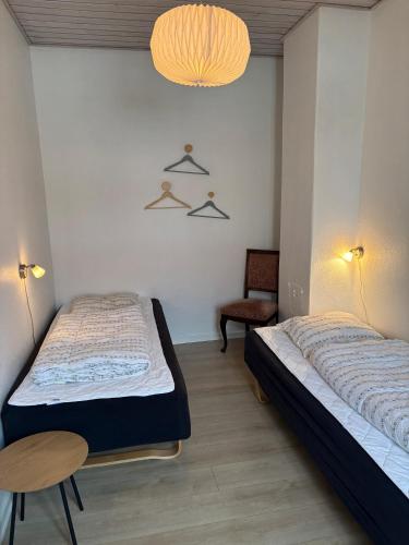 a bedroom with two beds and a table and a chair at Djursland Lystrup Strand Ferieboliger in Allingåbro